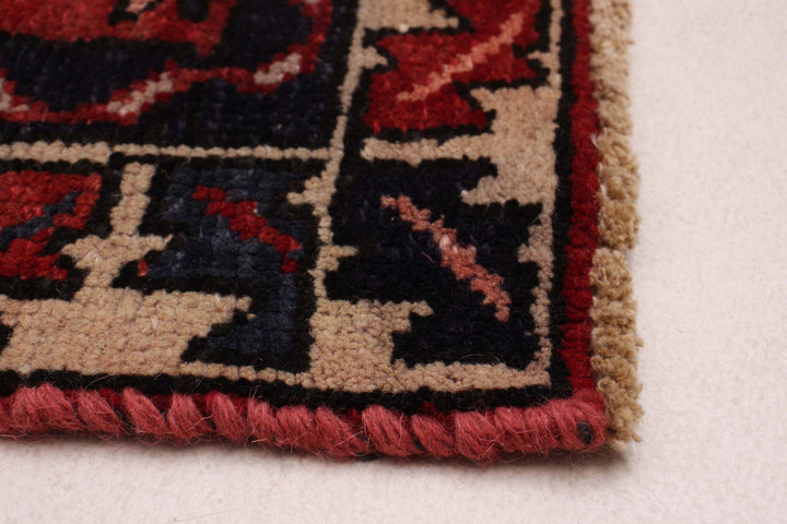 Close-up of the rug's edge, highlighting the hand-knotted finish and red-blue border. Available at Tuck Rugs.