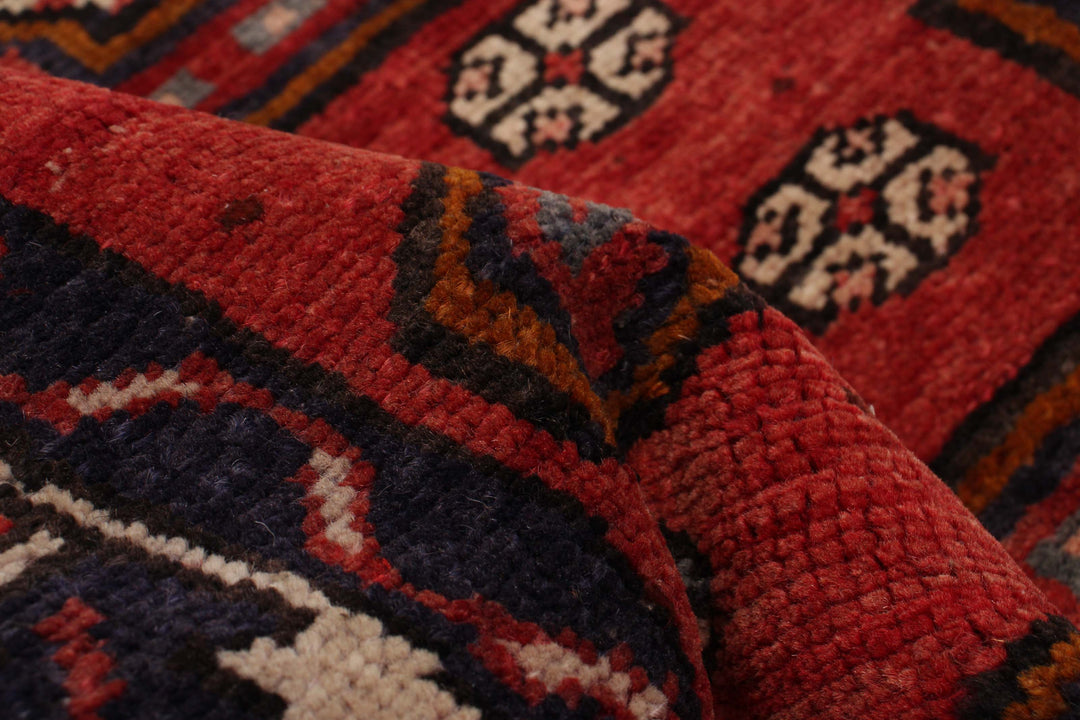 Close-up of the wool texture and geometric design with red and blue hues, showcasing fine craftsmanship. Available at Tuck Rugs.