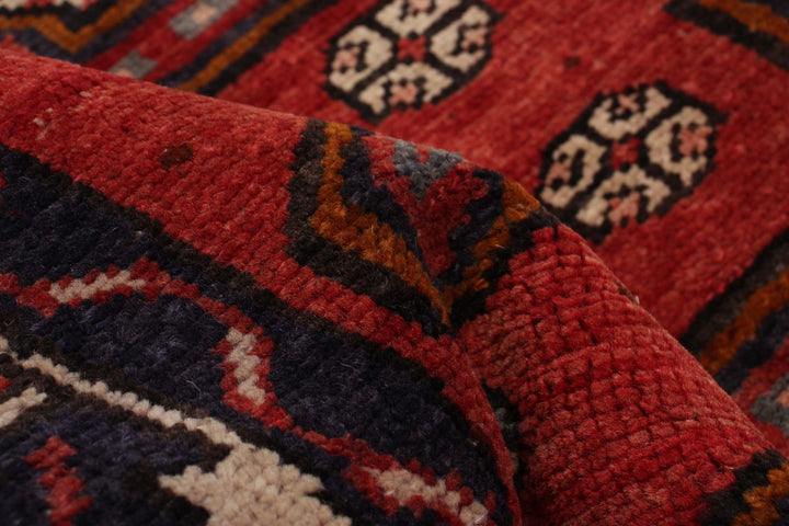 Close-up of the wool texture and geometric design with red and blue hues, showcasing fine craftsmanship. Available at Tuck Rugs.