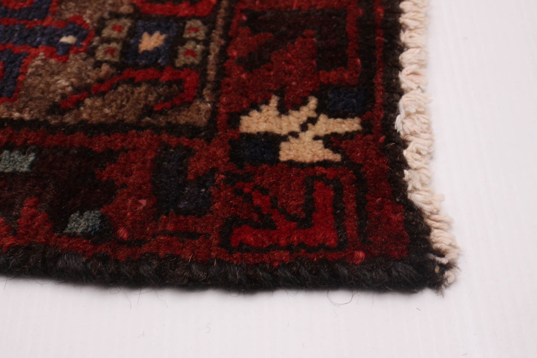 Close-up of the rug's edge with hand-knotted finishing and rich red and blue border patterns. Available at Tuck Rugs.