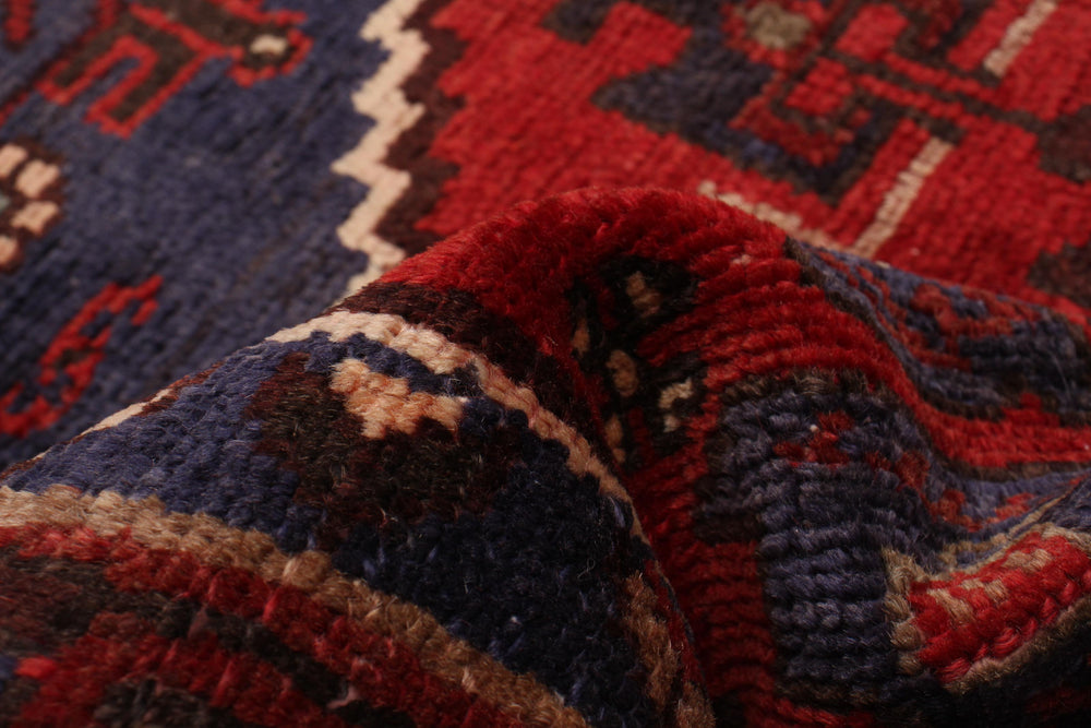 Close-up of the wool texture and geometric design with vibrant red and blue hues, highlighting intricate craftsmanship. Available at Tuck Rugs.