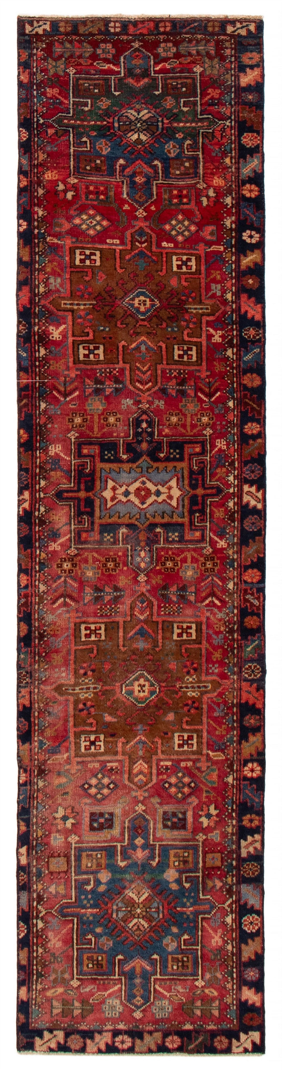 A long, narrow wool runner with red and blue geometric designs, hand-knotted with Persian-inspired motifs. Available at Tuck Rugs.