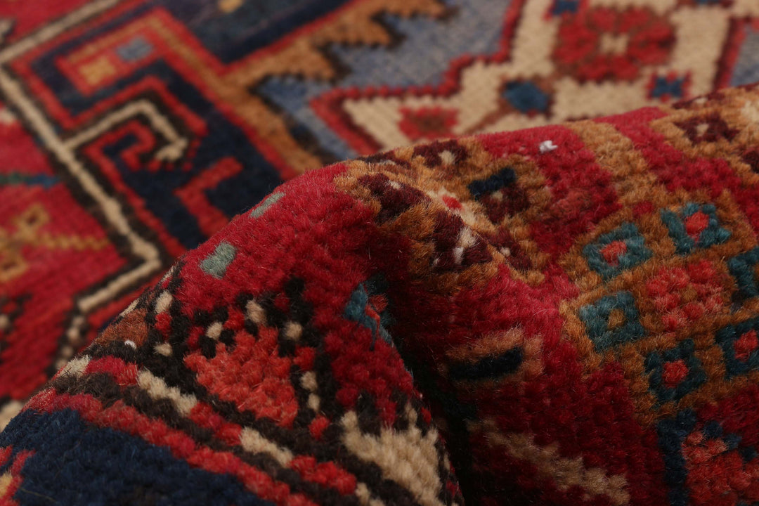 Close-up of hand-knotted wool runner showing geometric patterns in vibrant red and blue tones. Available at Tuck Rugs.