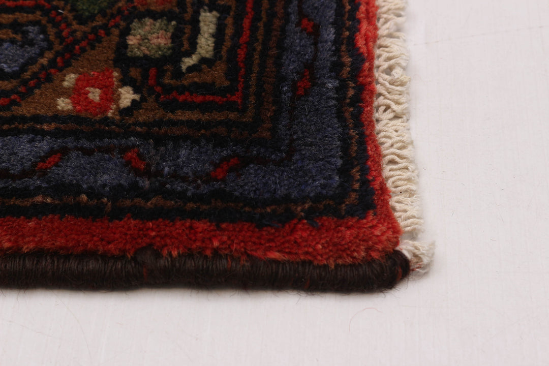 Close-up of the rug’s edge with hand-knotted details and bold red and blue border patterns. Available at Tuck Rugs.