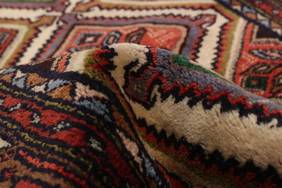 Close-up of the wool texture with intricate red, beige, and blue geometric patterns, highlighting fine craftsmanship. Available at Tuck Rugs.