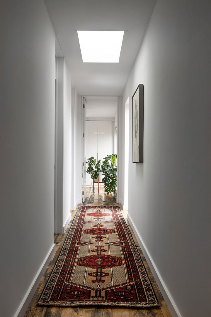 A long view of The Port City Turkish wool runner in a bright hallway, showcasing its detailed patterns. Available at Tuck Rugs.