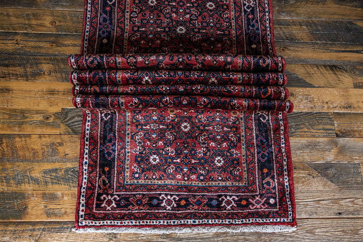 Close-up of The Crown Rug’s intricate hand-knotted design, highlighting vibrant red and black tones. Available at Tuck Rugs.